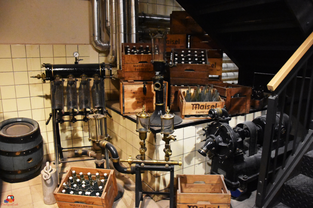 Einblick in die Brauerei: Alte Brauereiausrüstung und Holzboxen mit Flaschen im Maisel's Bier-Erlebnis-Welt in Bayreuth.