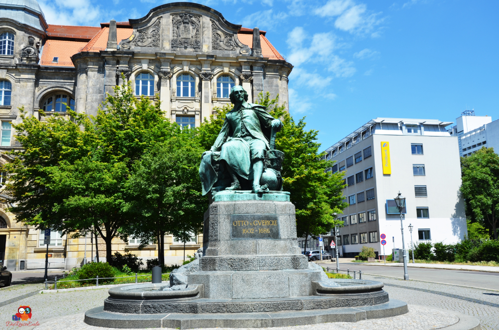 Denkmal für Otto von Guericke in Magdeburg, umgeben von Bäumen und historischen Gebäuden.