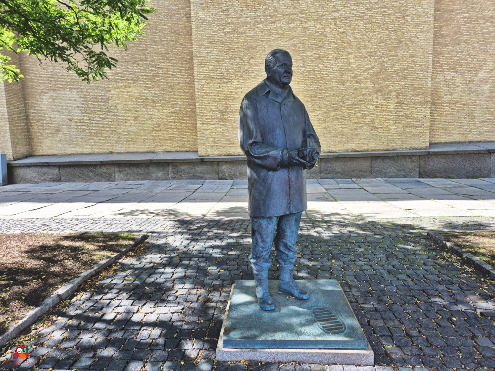 Bronzestatue eines Fotografen, der eine Kamera hält, vor einer hellen Backsteinmauer in Göteborg.