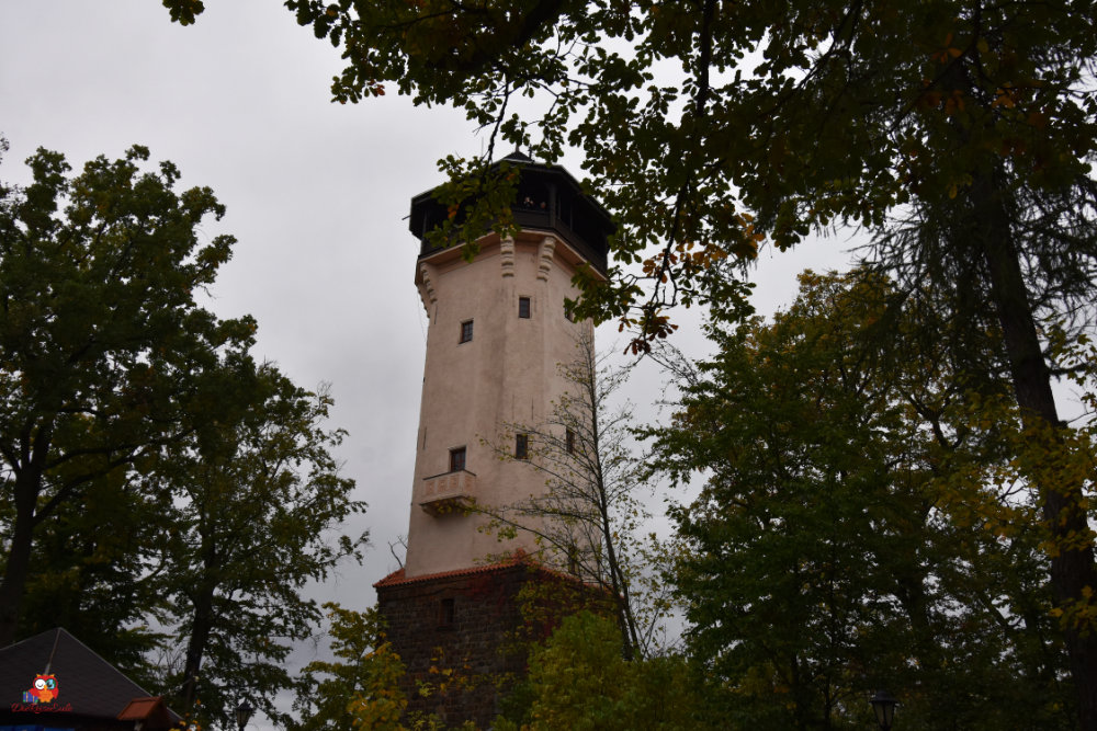 Ein hoher Wachturm umgeben von Bäumen unter einem bewölkten Himmel.