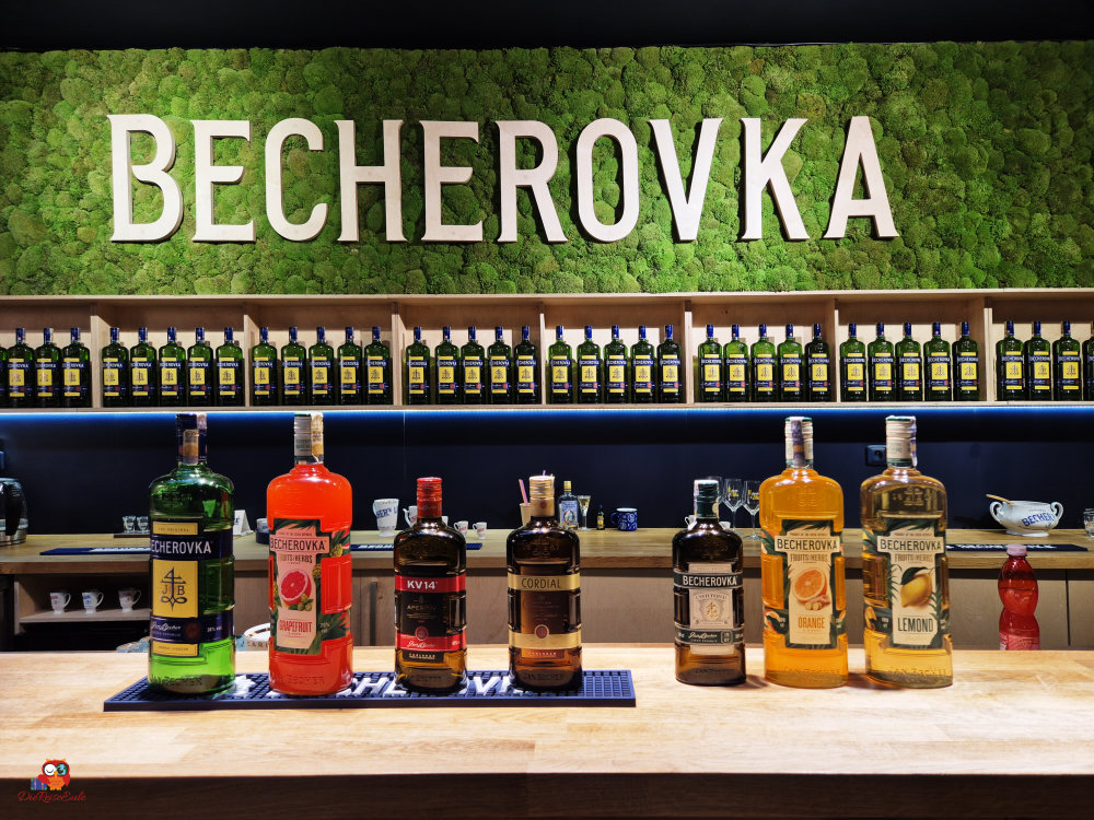 becherovka mehrere flaschen stehen vor dem firmenlogo