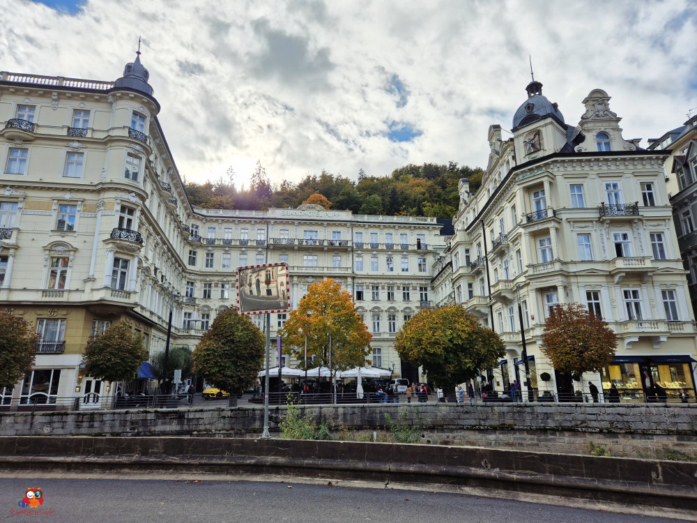 Ein Blick auf das Grand Hotel mit historischen Gebäuden und herbstlichen Bäumen in einer Stadtlandschaft.