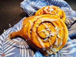 zimtschnecken auf einem blauen küchenhandtuch mit weisen farnblättern
